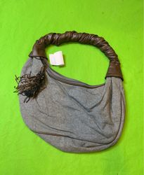 Gray hobo bag with brown leather handles and tasse..