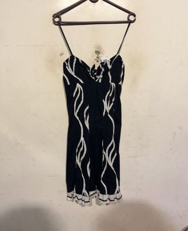Schwarzes Kleid mit weißem Wirbelmuster und Rüschensaum