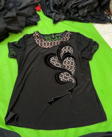 Black top with lace sleeves and embellished front, and a black lace-trimmed skirt