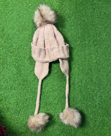 Rosa gestrickte Mütze mit Ohrenschützern und Bommel