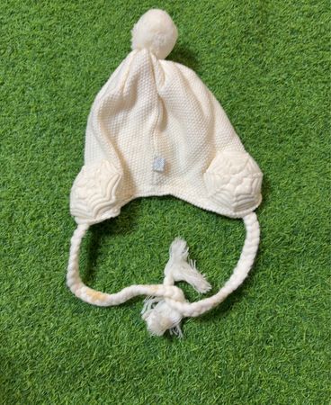 Weiße Strickmütze mit Pompon und Ohrenklappen