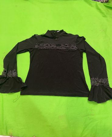 Chemise noire à manches longues avec des détails en dentelle sur les manches et la poitrine.