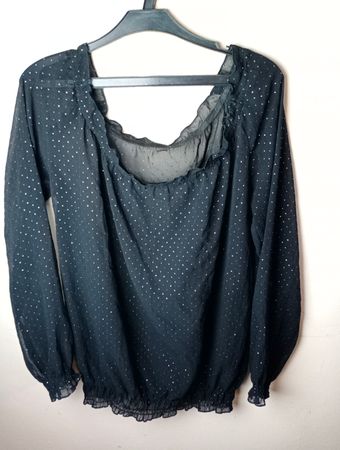 Schwarze durchsichtige Bluse mit Punkten und Rüschenhalsausschnitt und -ärmeln.