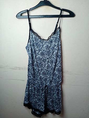 Blauer und weißer Blumenmuster-Overall mit schwarzem Spitzenbesatz.