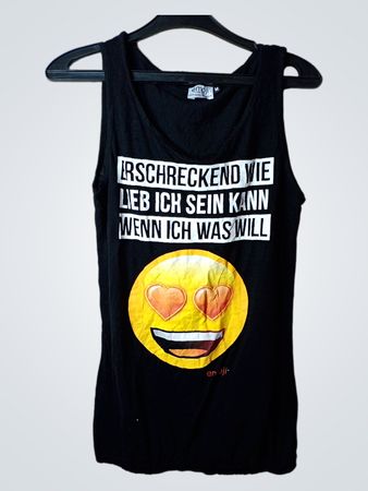 Schwarzes Tanktop mit dem Text „erschreckend wie lieb ich sein kann wenn ich was will“ und Herzaugen-Emoji-Grafik