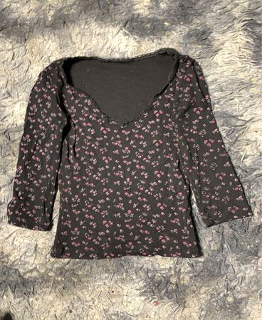 Schwarzes Langarmoberteil mit floralem Druck und rosa Blumen.
