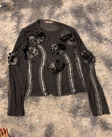 Schwarzes Langarmshirt mit floralem Schmuck.