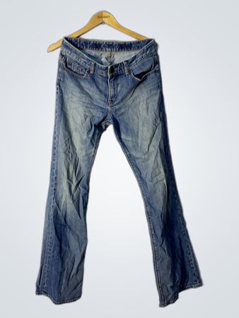 Blaue ausgestellte Jeans mit Verzierungen auf den Gesäßtaschen.