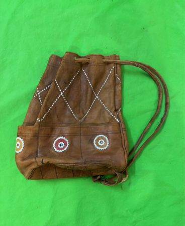 Braune Lederzugtasche mit weißen und roten Verzierungen