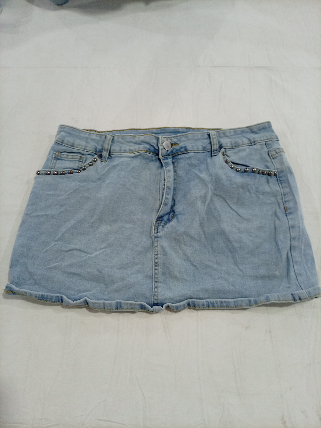 Jupe en denim clair avec accents de poches en chaî..