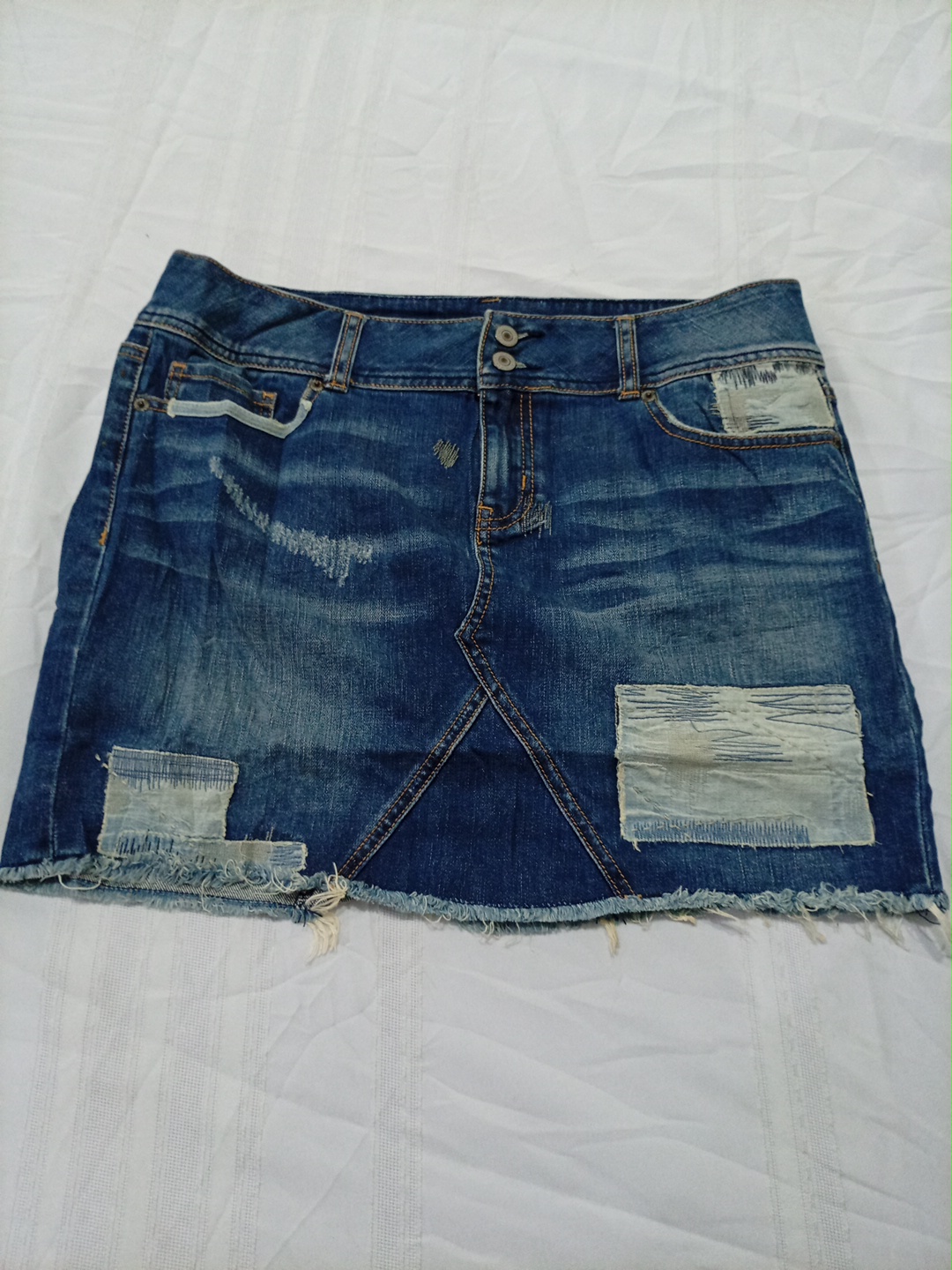 Mini-jupe en denim usé avec des patchs par London ..