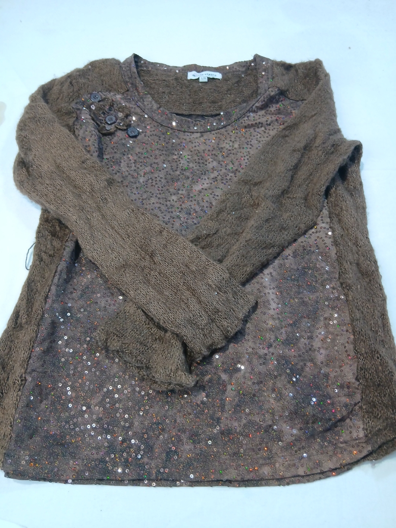 ブラウンのスパンコールトップとニットセーターの袖